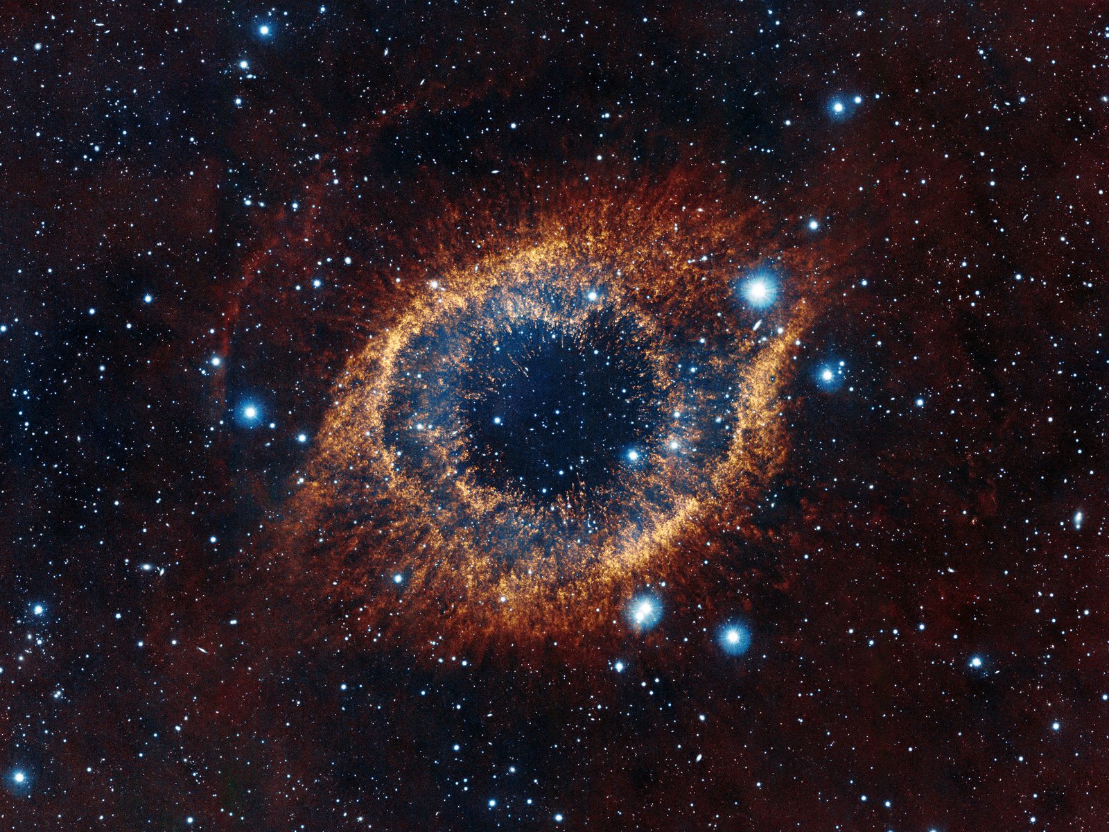 ESO's Visible and Infrared Survey Telescope for Astronomy (VISTA) has captured this unusual view of the Helix Nebula (NGC 7293), a planetary nebula located 700 light-years away. The coloured picture was created from images taken through Y, J and K infrared filters. While bringing to light a rich background of stars and galaxies, the telescope's infrared vision also reveals strands of cold nebular gas that are mostly obscured in visible images of the Helix. 